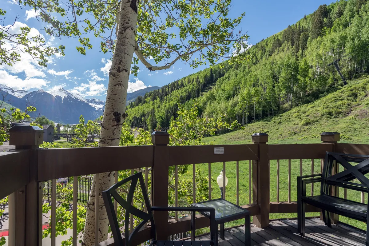 A tranquil outdoor deck with comfortable seating, lush greenery, and uninterrupted views of the mountains. The inviting furniture and natural surroundings make this a perfect space for morning coffee or evening drinks, seamlessly extending the living experience outdoors.
