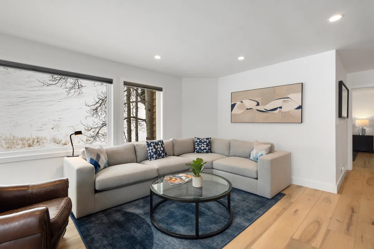 A serene lounge area featuring a comfortable sofa and coffee table, bathed in natural light from large windows that frame scenic views. Thoughtful touches like artwork on the walls and ample space for socializing or relaxing make this spot perfect for both quiet moments and lively gatherings.